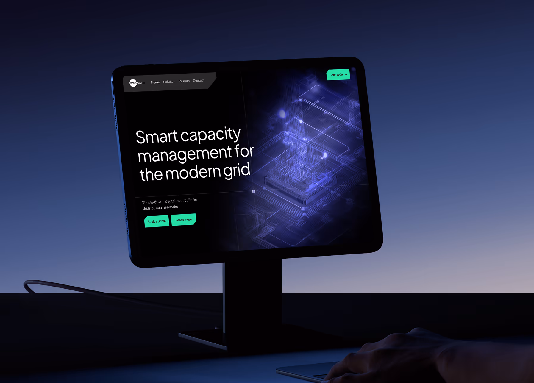 Desktop monitor on a stand displaying a dark-themed webpage about smart capacity management for modern grids with a digital network illustration, glowing in blue light.